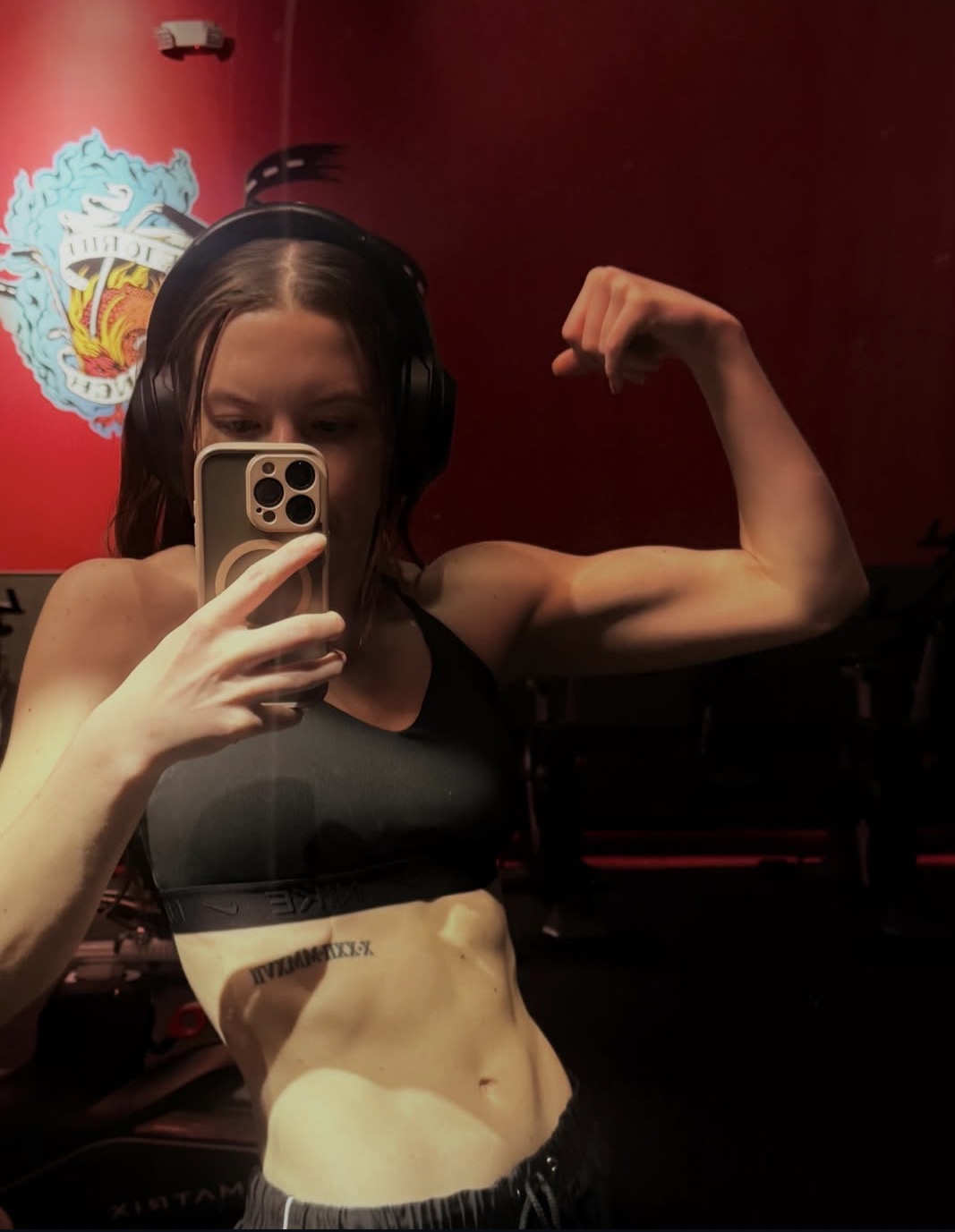 Athlete flexing in a gym with headphones